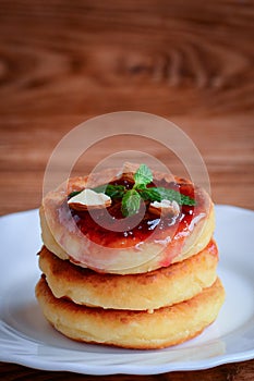 Delicious homemade cottage cheese pancakes. Simple cottage cheese pancakes with berry jam and nuts. Vertical photo. Closeup