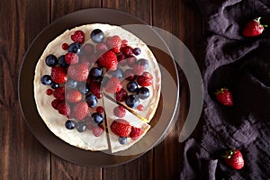 Delicious Homemade creamy mascarpone New York Cheesecake with berries on dark wooden table. Top viev.