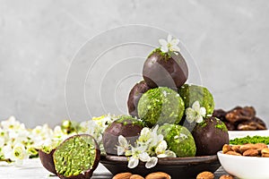 Delicious homemade energy balls with matcha tea, coconut, dates and almonds in chocolate glaze with blossom flowers