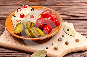 Delicious homemade fermented vegetables on a plate sauerkraut, pickled tomatoes, pickles, wooden background