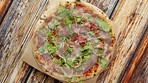 Delicious homemade Italian prosciutto and rucola pizza placed on wooden background