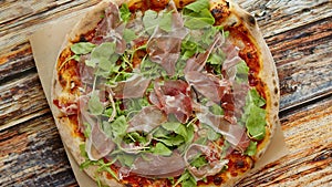 Delicious homemade Italian prosciutto and rucola pizza placed on wooden background