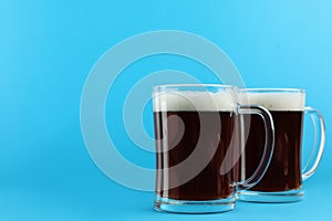 Delicious homemade kvass in glass mugs on blue background. Space for text