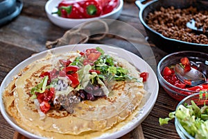 Savory pancakes with meat and vegetables on a wooden table