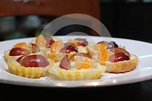 Delicious homemade mini fruit pies with orange slice and grape slices on a white ceramic plate