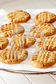 Delicious homemade peanut butter cookies on cooling rack. White wooden background. Healthy snack concept.