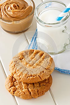 Delicious homemade peanut butter cookies with mug of milk. White wooden background. Healthy snack or tasty breakfast concept.