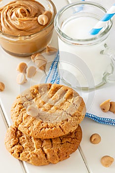 Delicious homemade peanut butter cookies with mug of milk. White wooden background. Healthy snack or tasty breakfast concept