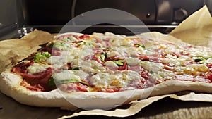 Delicious Homemade Pizza baking inside the oven for a social gathering of family and friends. Pizza on Baking Paper in a