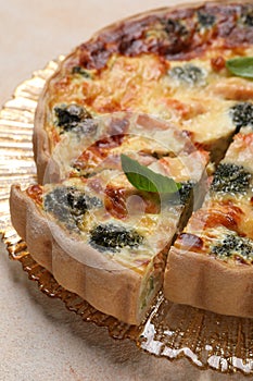 Delicious homemade quiche with salmon and broccoli on beige table, closeup