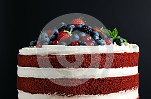 Delicious homemade red velvet cake with fresh berries on black background