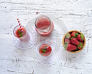 Delicious homemade strawberry smoothie on rustic white wooden background