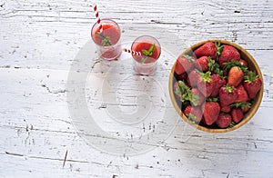 Delicious homemade strawberry smoothie on rustic white wooden background