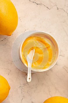 Delicious homemade tangy lemon curd decorated with fresh fruit on marble background.Top view