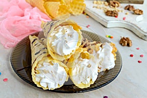 Delicious honeyed waffles, twisted into cones with cream, nuts, chocolate topping on the plate