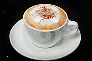 Delicious hot Cappuccino with cinnamon in a white cup. photo