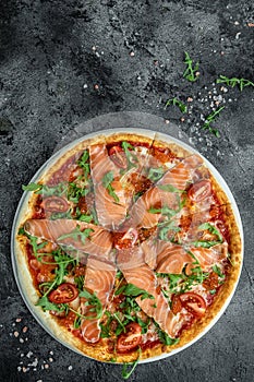 Delicious hot pizza with salmon, red caviar, tomatoes and aragula ready to eat. vertical image. top view. place for text