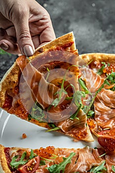 Delicious hot pizza with salmon, red caviar, tomatoes and aragula ready to eat. vertical image. top view. place for text