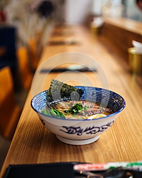 Delicious hot warming japanese ramen noodles soup in a traditional blue bowl on the table, upright