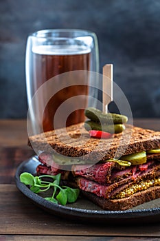 Delicious huge pastrami sandwich with beer and pickle