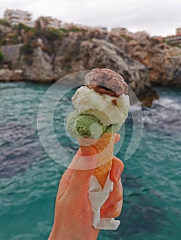 Delicious ice cream on the background of rocks and the sea. Aegean coast.