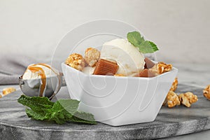 of delicious ice cream with caramel candies, popcorn and mint on table