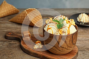 Delicious ice cream with caramel popcorn and sauce served on table