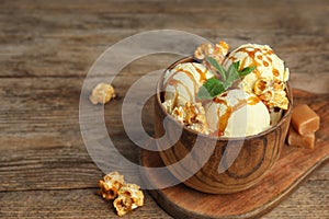 Delicious ice cream with caramel popcorn and sauce served on table