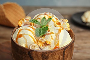 Delicious ice cream with caramel popcorn and sauce served on table