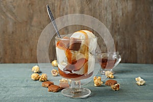 Delicious ice cream with caramel topping in dessert bowl on wooden table