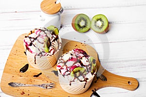 Delicious ice cream in a cup with chocolate sauce and tasty fruits