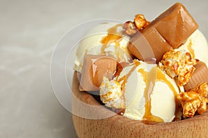 Delicious ice cream served with caramel popcorn and sauce on table, closeup.