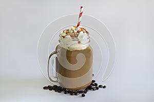 Delicious iced coffee or Frappuccino with whipped cream , syrup and a red straw . With Coffee beans isolated on white background