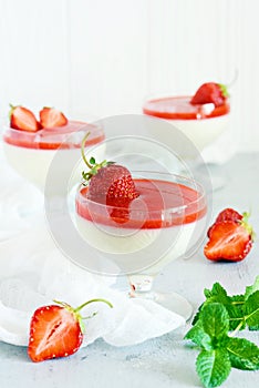 Delicious italian dessert panna cotta  with strawberry sauce, strawberries and fresh mint leaves. Summer creamy dessert