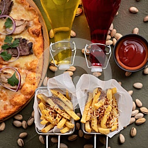 Delicious Italian food on table. Pizza, French fries, oil or wine bottles, ketchup and pistachios on it. Flat lay or top