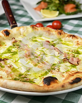 Delicious italian pizza, with sauce, peppers, bacon and zucchini on wooden table background