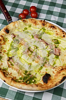 Delicious italian pizza, with sauce, peppers, bacon and zucchini on wooden table background