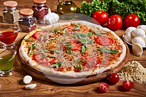 Delicious italian pizza served on wooden table. Pizza margarita with tomato sauce, fresh mozzarella, parmesan and basil on the