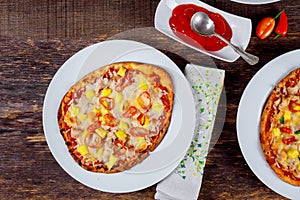 Delicious italian pizzas served on wooden table with ingredients shot from above