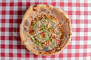 Delicious italian pizzas served on wooden table with red plaid table cloth