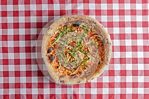 Delicious italian pizzas served on wooden table with red plaid table cloth
