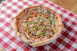 Delicious italian pizzas served on wooden table with red plaid table cloth