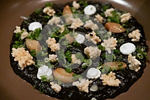 Delicious Italian risotto with cuttlefish ink or squid-ink with cauliflower. Black risotto. Healthy gourmet food.