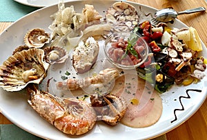 Delicious Italian seafood and fish antipasti platter as appetizer on wooden restaurant table. Gourmet food close up