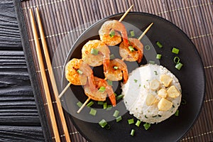 Delicious Japanese garlic fried rice served with shrimp kebabs close-up in a plate. horizontal top view