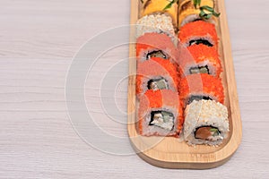 Delicious Japanese rolls with salmon, avocado, cucumber, cheese on wooden plate with selective focus. Asian food concept
