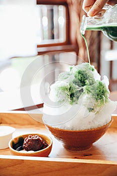 Delicious Japanese sweet shaved ice green tea on wooden table in japanese cafe