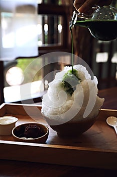 Delicious Japanese sweet shaved ice green tea on wooden table in japanese cafe