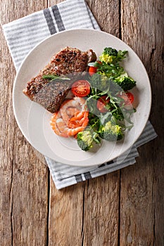 Delicious juicy barbequed steak and prawns with vegetable salad