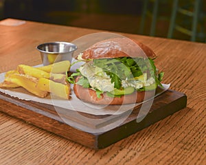 Delicious juicy chef cheeseburger served with fries on a rustic wooden board on a table in bar or restaurant